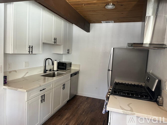 A kitchen with white cabinets and a stove top oven.