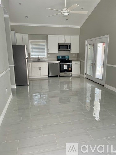 A kitchen with white cabinets and a black fridge.