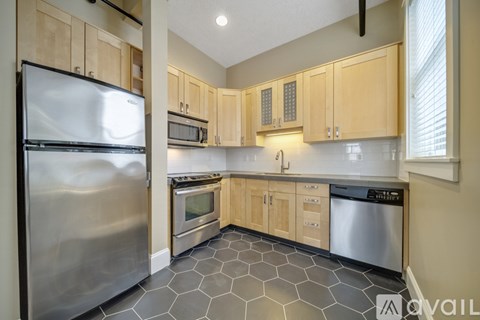 A kitchen with a stainless steel refrigerator and a black and white tiled floor.