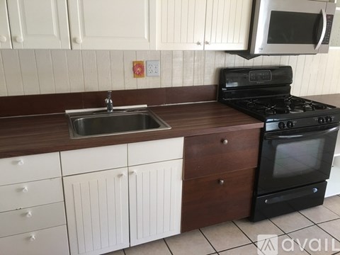 A kitchen with a sink, stove, and cabinets.