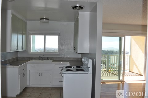 A kitchen with white appliances and cabinets with a balcony in the background.