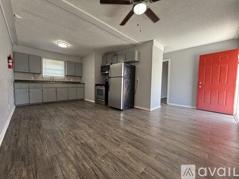 A room with a red door and a wooden floor.