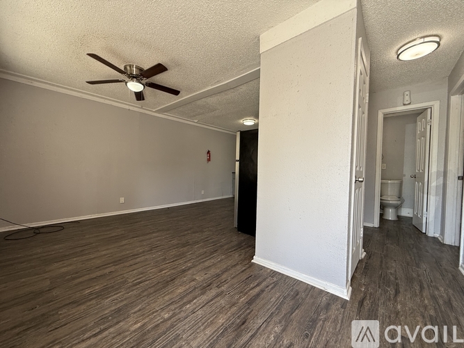 A room with a ceiling fan and wood flooring.