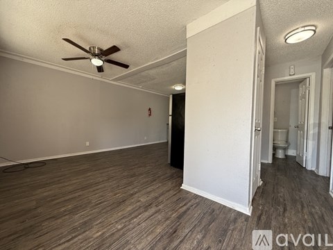 A room with a ceiling fan and wood flooring.