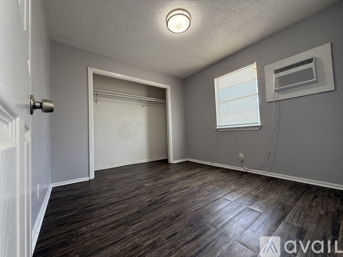 A room with a door, window, and a wall-mounted air conditioner unit.