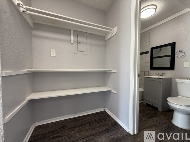 A bathroom with a toilet, sink, and shelves.