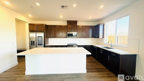 A modern kitchen with dark wood cabinets and a white island.