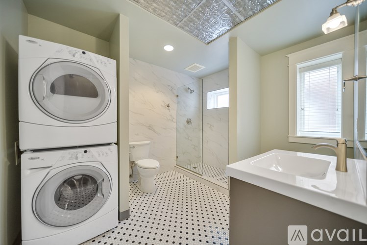 A bathroom with a washer and dryer stacked on top of each other.
