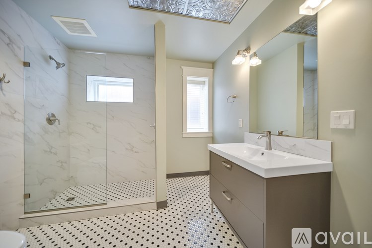 A bathroom with a marble shower and a white sink.