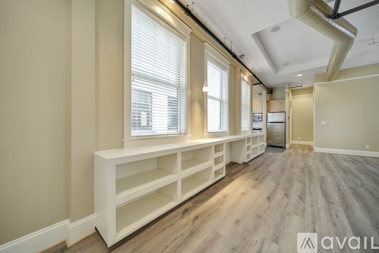 A spacious room with wooden flooring and built-in shelves.