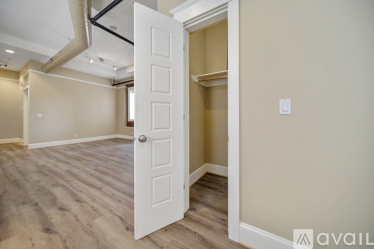 A room with a white door and wooden flooring.