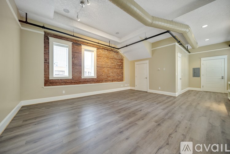 A spacious room with wooden floors and exposed pipes on the ceiling.