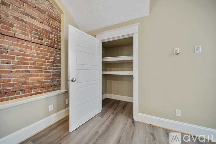 A room with a white door and a brick wall.