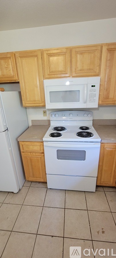 A kitchen with a white stove and wooden cabinets.
