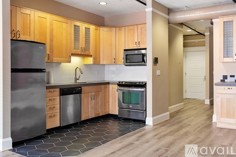 A kitchen with wooden cabinets and a black refrigerator.