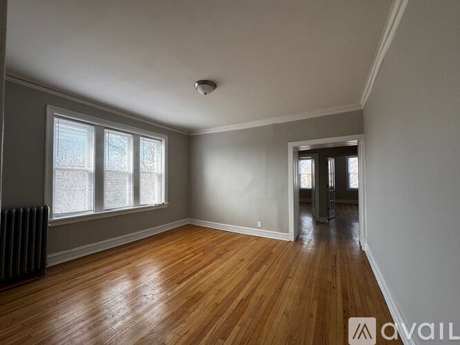 A room with wooden floors and a window with a view of a snowy landscape.