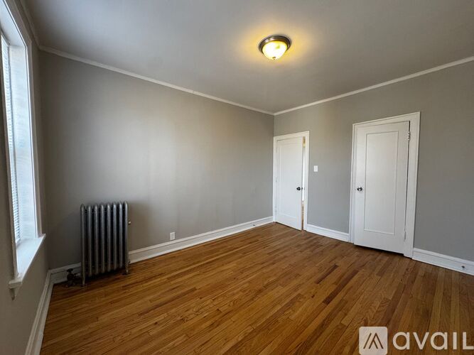 A room with wooden floors and a window on the left side.