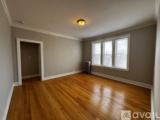 A room with wooden floors and a window with a view of a snowy landscape.