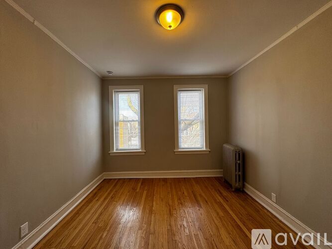 A room with wooden floors and two windows.