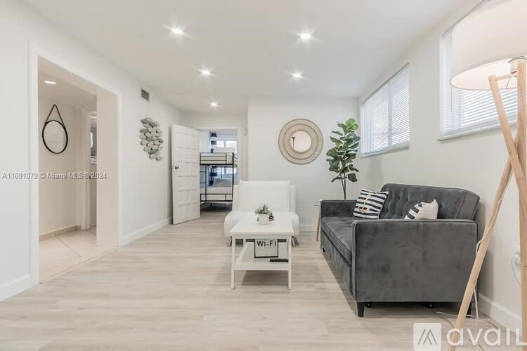 A living room with a grey couch, a white coffee table, and a wooden floor.