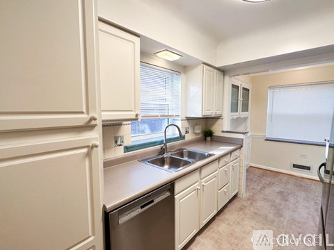 A kitchen with white cabinets and a stainless steel dishwasher.