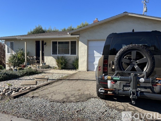 A black SUV is parked in a driveway in front of a house.