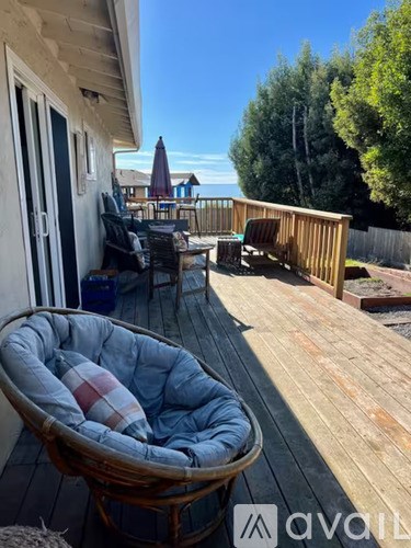 A deck with a wicker chair and a blue and red striped cushion.