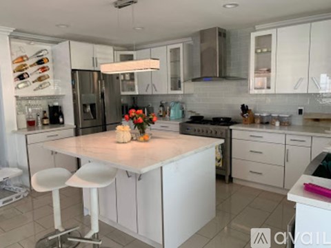 A kitchen with white cabinets and a marble island.