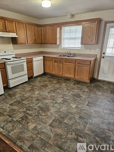 A kitchen with wooden cabinets and a stone floor.