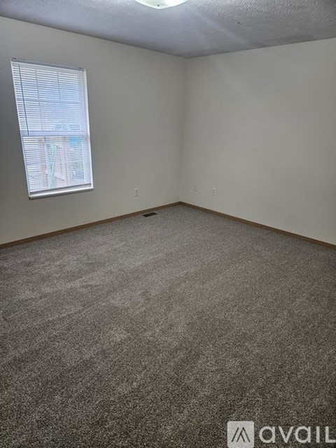 A room with a carpeted floor and a window with blinds.