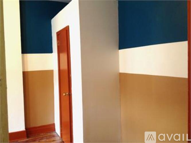 A room with a brown door and a white wall.
