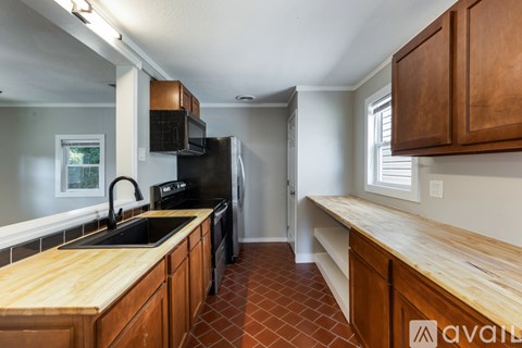 A kitchen with wooden cabinets and a black refrigerator.