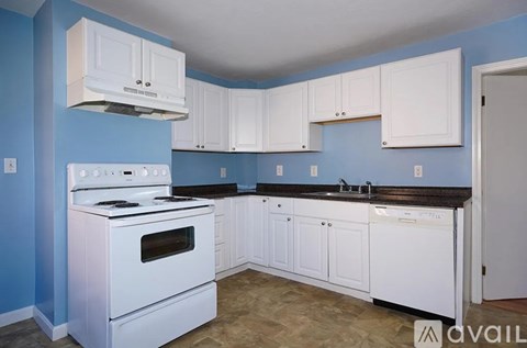 A kitchen with white cabinets and a white stove.