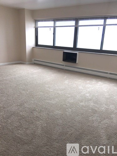 A room with a carpeted floor and a window with blinds.