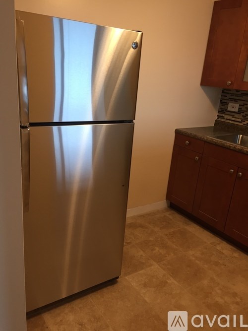 A stainless steel refrigerator in a kitchen with wooden cabinets.
