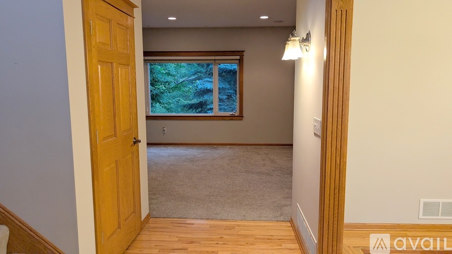A room with a carpeted floor and a window with a view of trees.