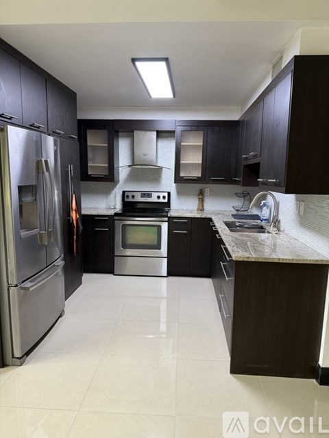 A modern kitchen with dark brown cabinets and stainless steel appliances.