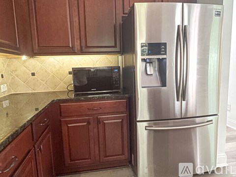 A kitchen with a stainless steel refrigerator and wooden cabinets.