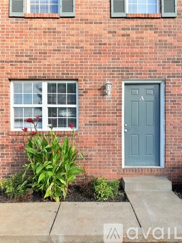 A brick house with a grey door and a window with white blinds.