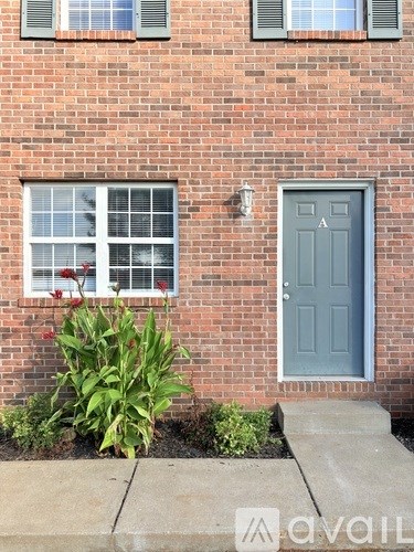 A brick house with a grey door and a window with white blinds.