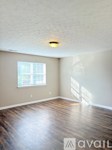 A room with a window and wooden flooring.