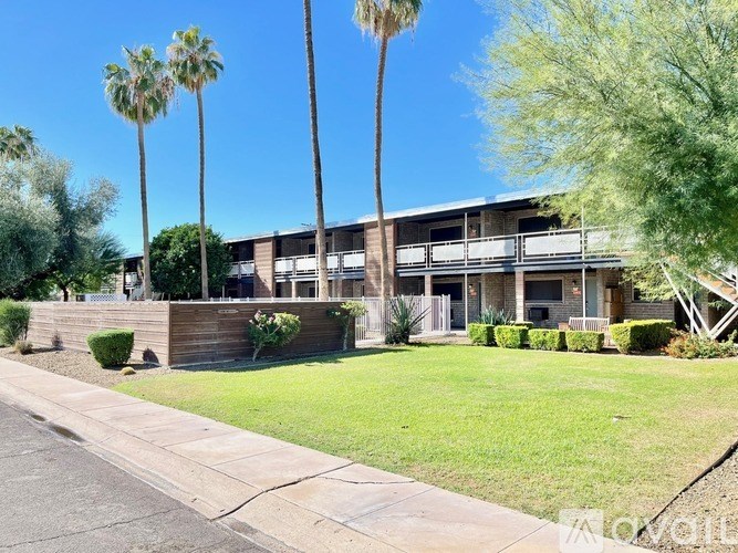 A building with a balcony and palm trees in front.