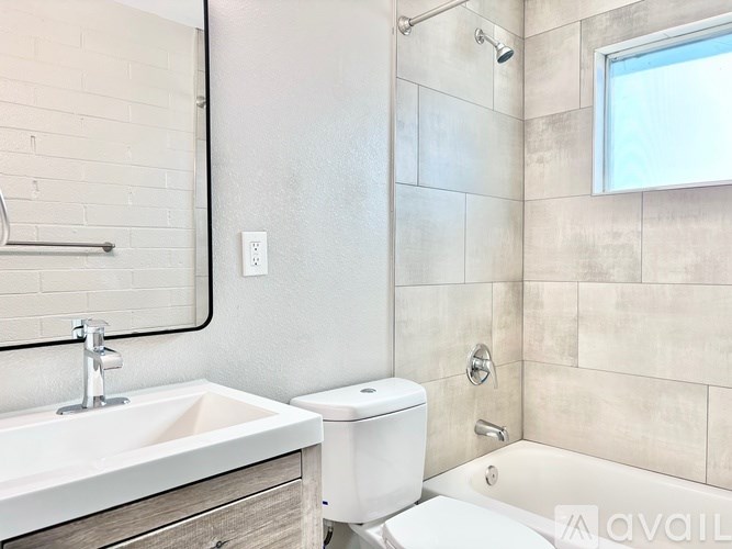 A bathroom with a white toilet, sink, and tiled walls.