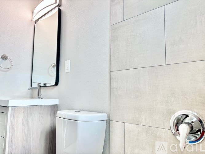 A bathroom with a toilet, sink, and mirror.