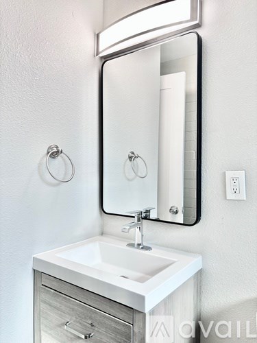 A white sink with a silver faucet and a mirror above it.