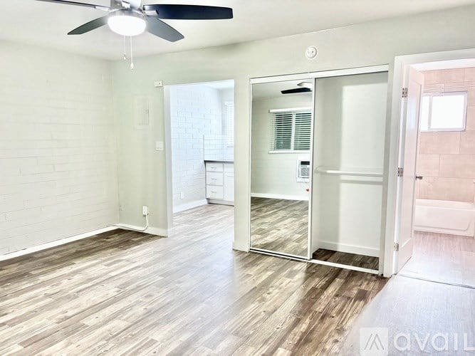 A room with a fan and a mirror on the wall.