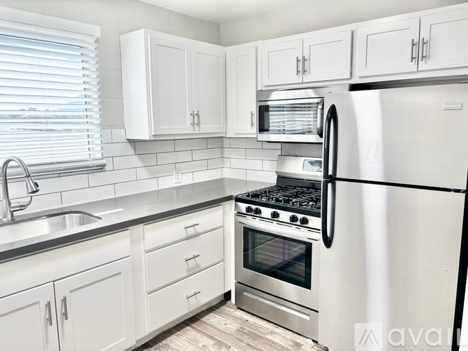 A kitchen with white cabinets and a stainless steel refrigerator.