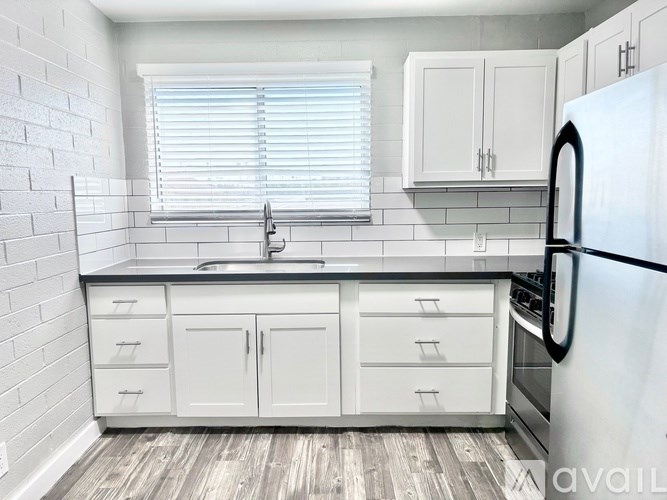 A kitchen with white cabinets and a black fridge.