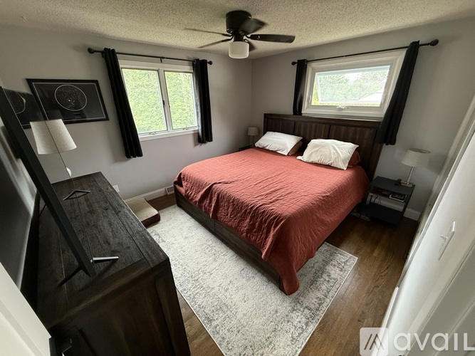 A bedroom with a red bedspread and a ceiling fan.
