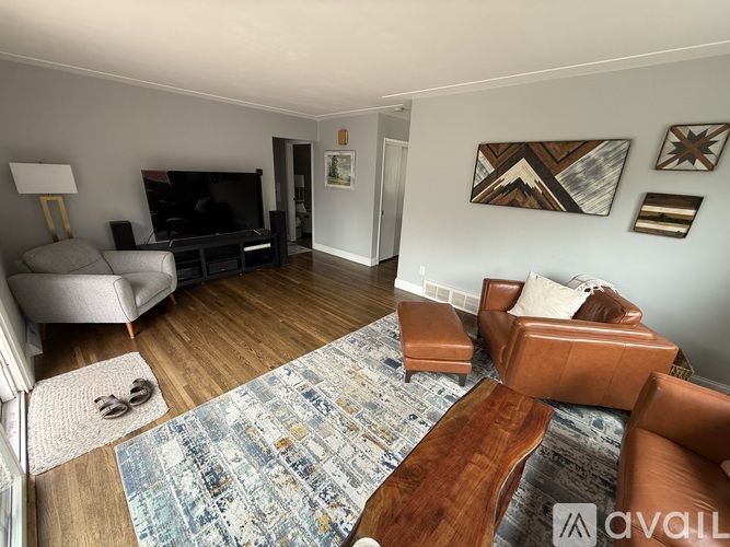 A living room with a brown leather couch and a blue patterned rug.